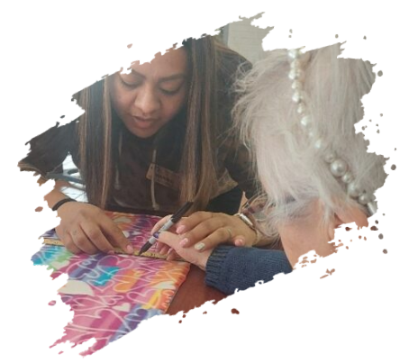 Young woman assisting elderly person with crafts. Colorful fabric, indoors.