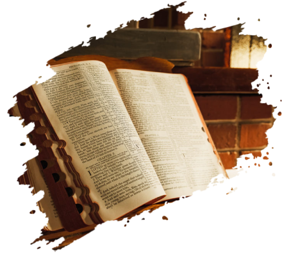 Open book on a desk, with text visible on the pages. A stack of books and a brick wall are in the background.