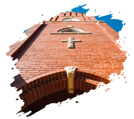 Red brick church tower with a cross and arched entryway, looking up.