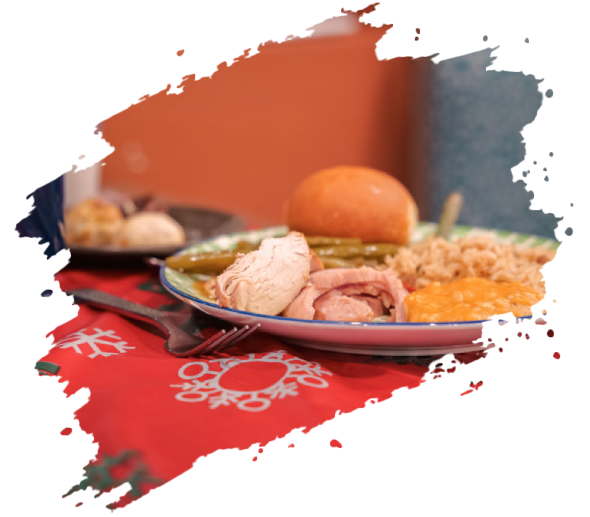 Plate of food with turkey, roll, vegetables, and stuffing on a red tablecloth.