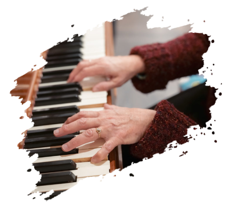 Hands playing a piano; wearing a maroon sweater, the keyboard is in focus.