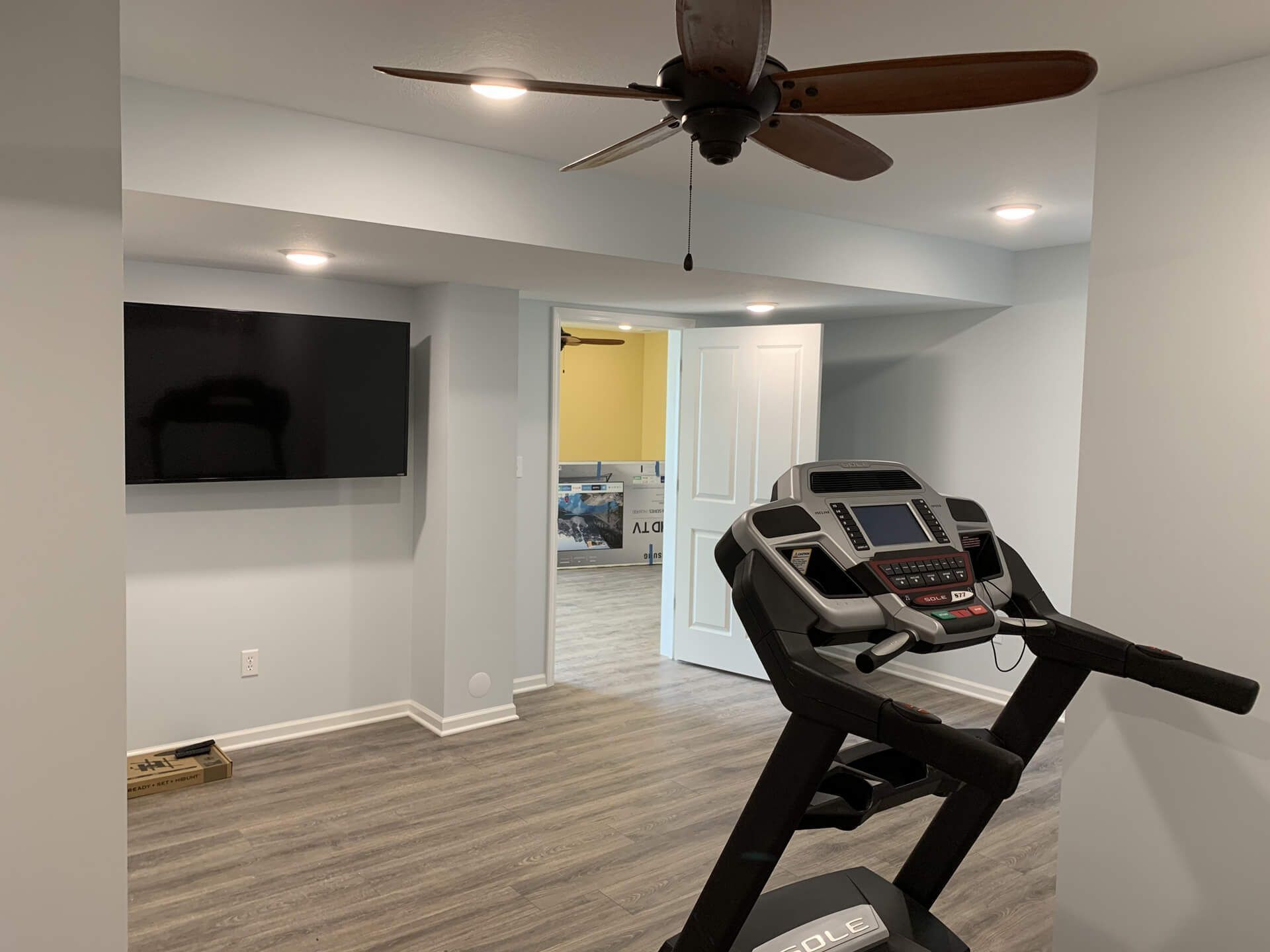 Treadmill in A Basement with A Ceiling Fan and A Flat Screen TV — Columbia, MO — Naugle Construction Company