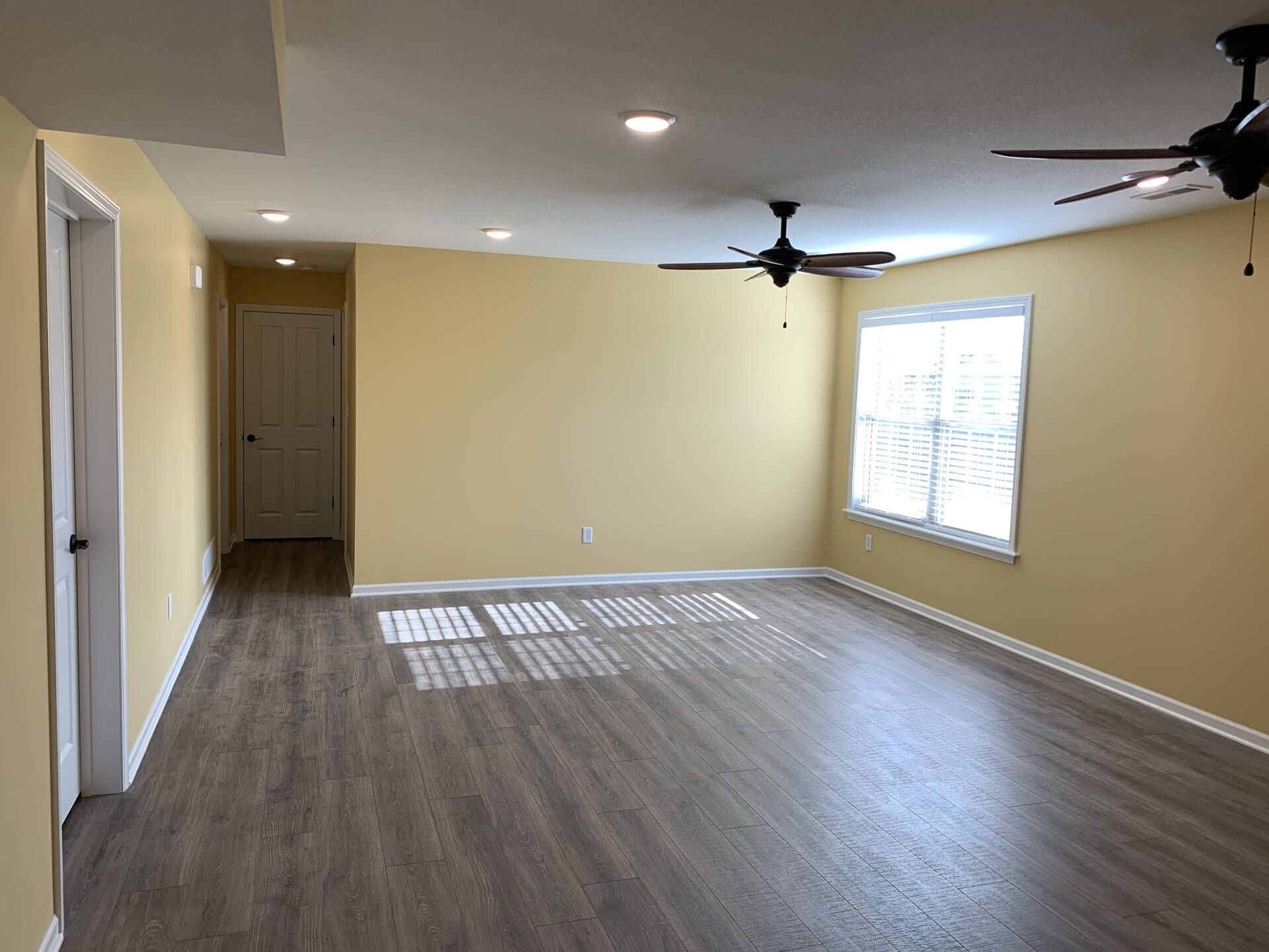 Empty Living Room with Yellow Walls and A Ceiling Fan — Columbia, MO — Naugle Construction Company