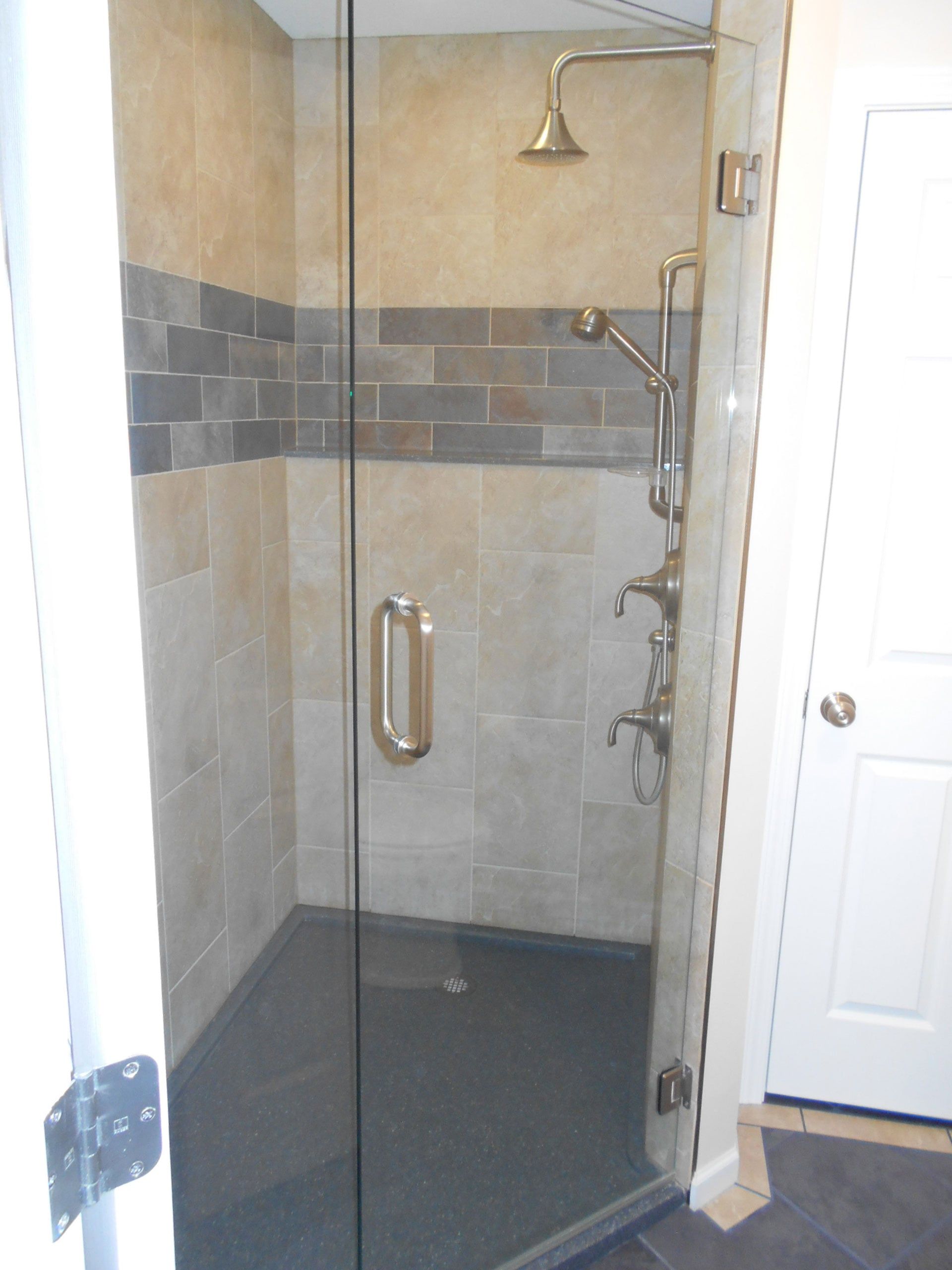 A Walk in Shower with A Glass Door and A Shower Head — Columbia, MO — Naugle Construction Company