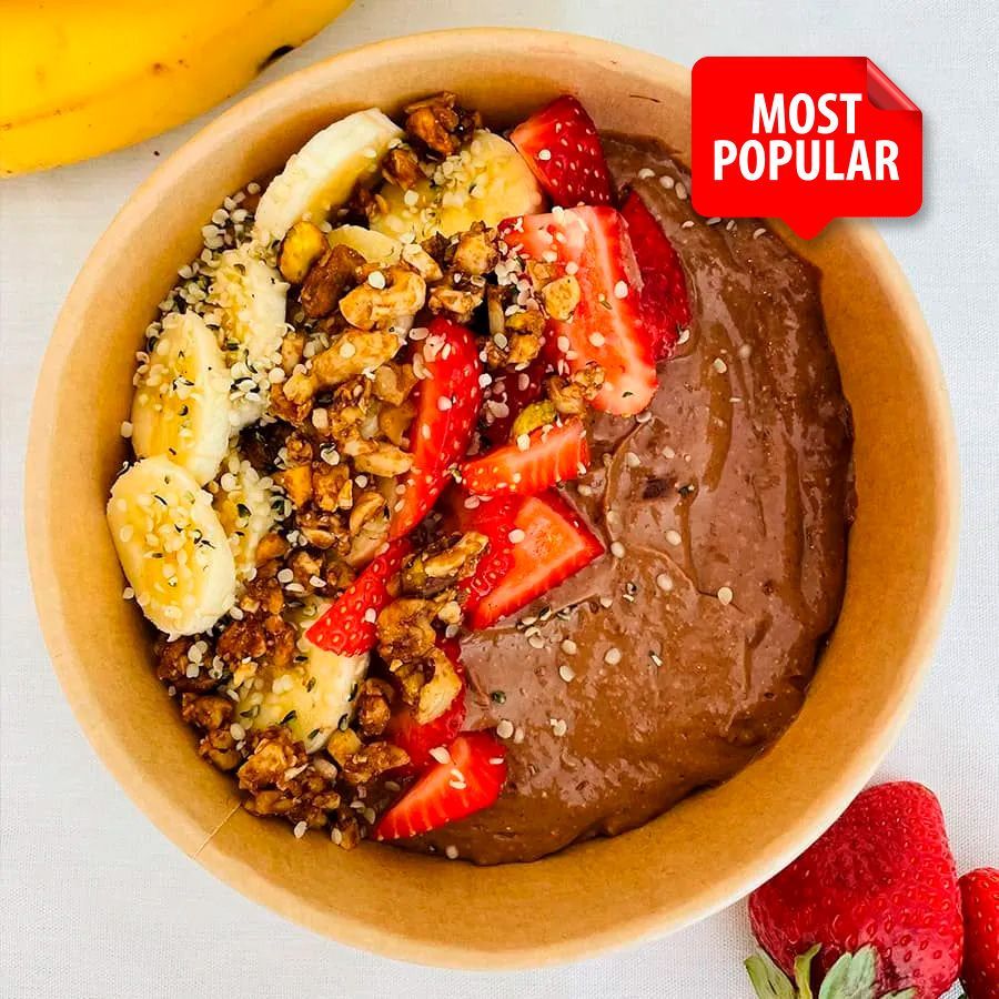 A bowl of chocolate pudding with bananas and strawberries