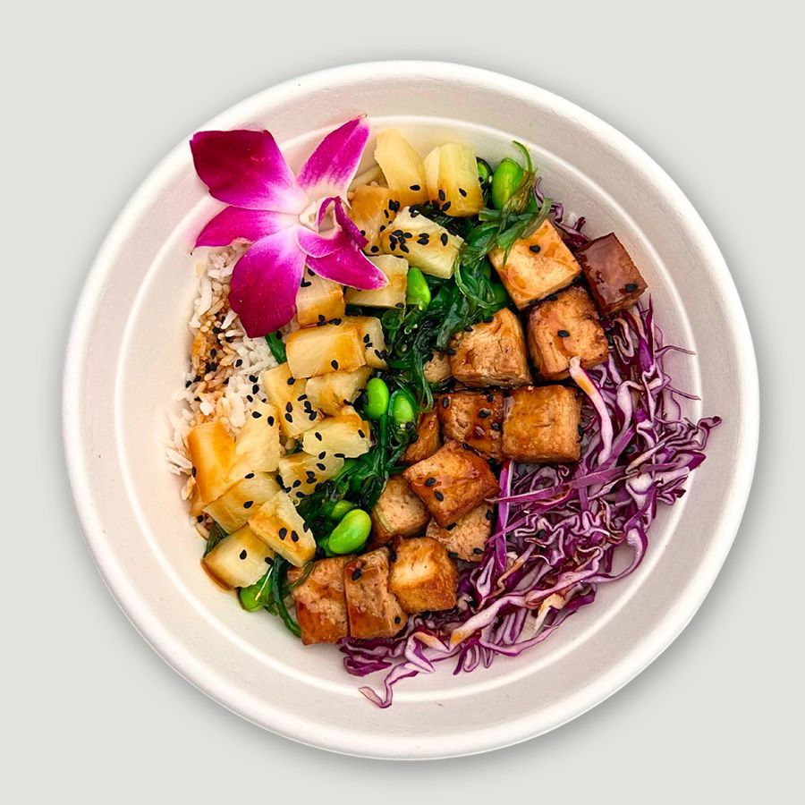 A bowl of food with rice , cabbage , and edamame beans on a table.