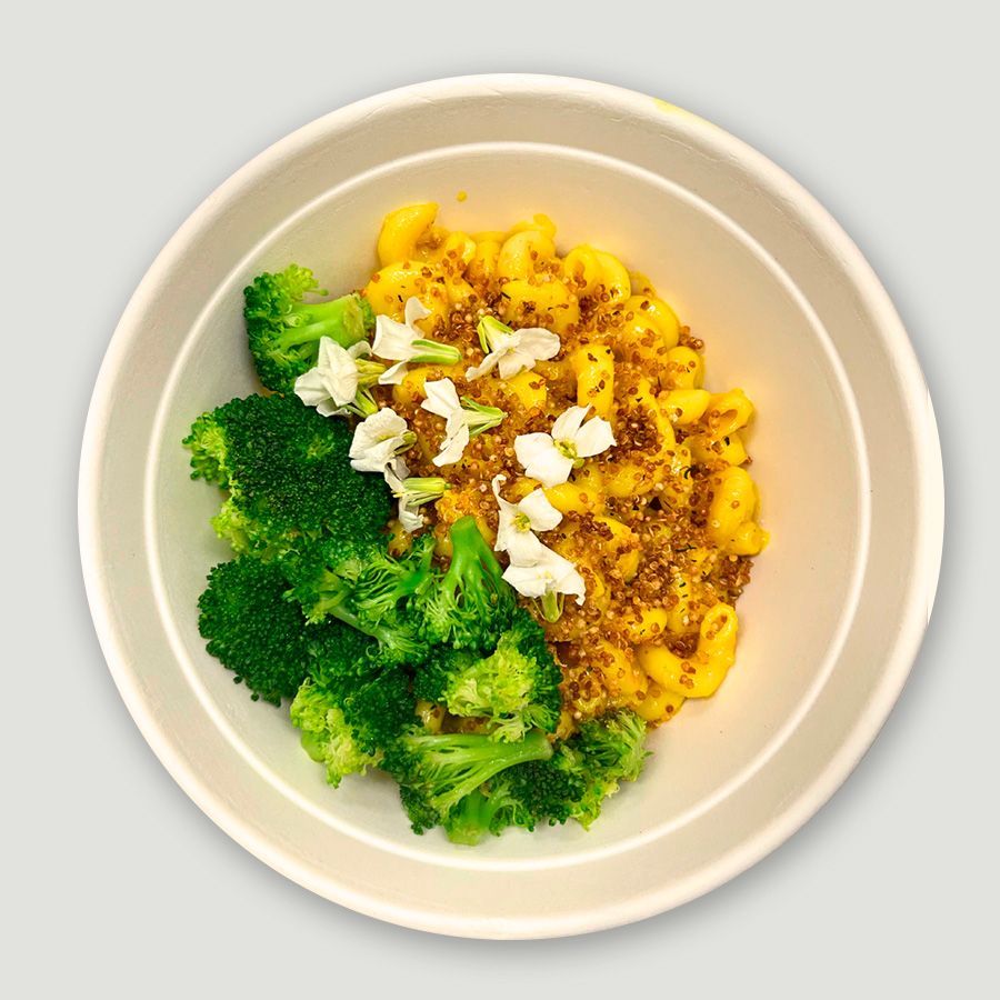 A white bowl filled with macaroni and cheese and broccoli.