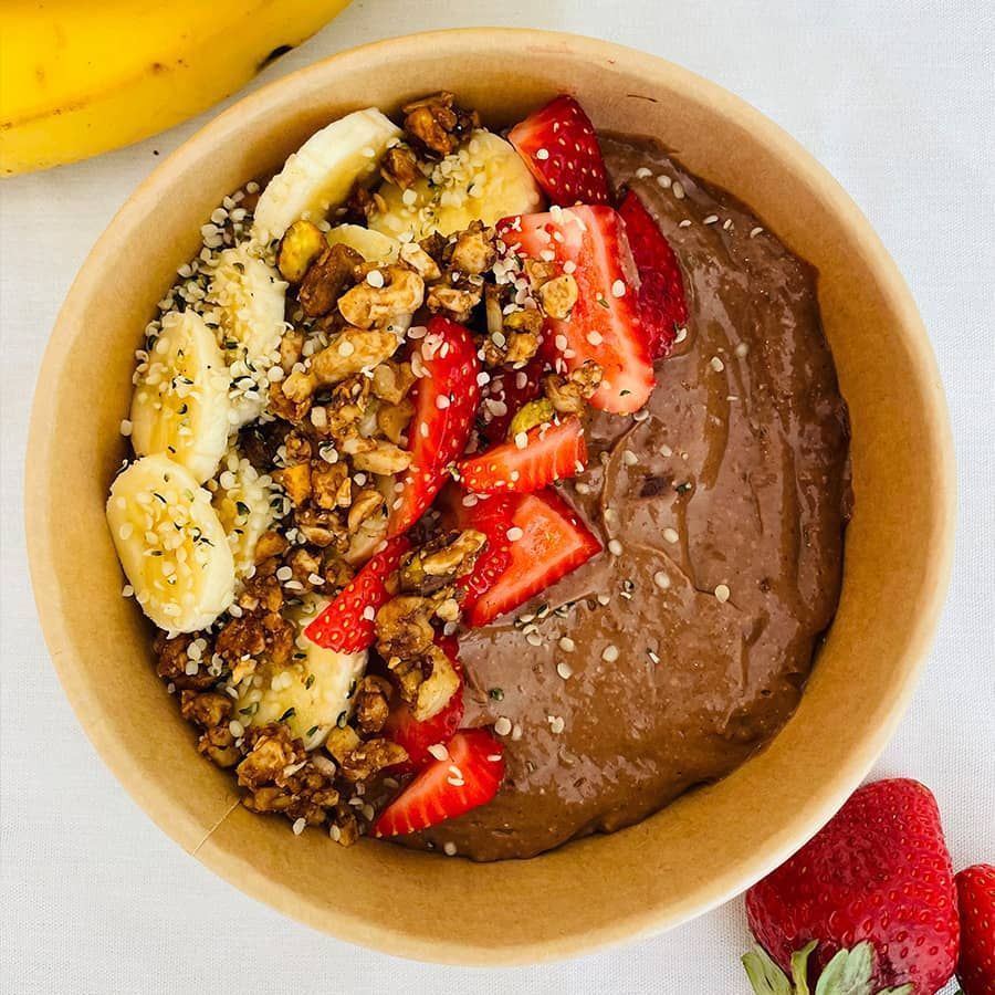 A bowl of chocolate pudding with bananas and strawberries on top