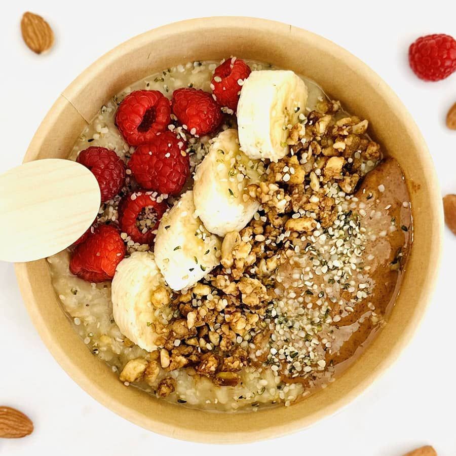 A bowl of oatmeal with bananas , raspberries and nuts
