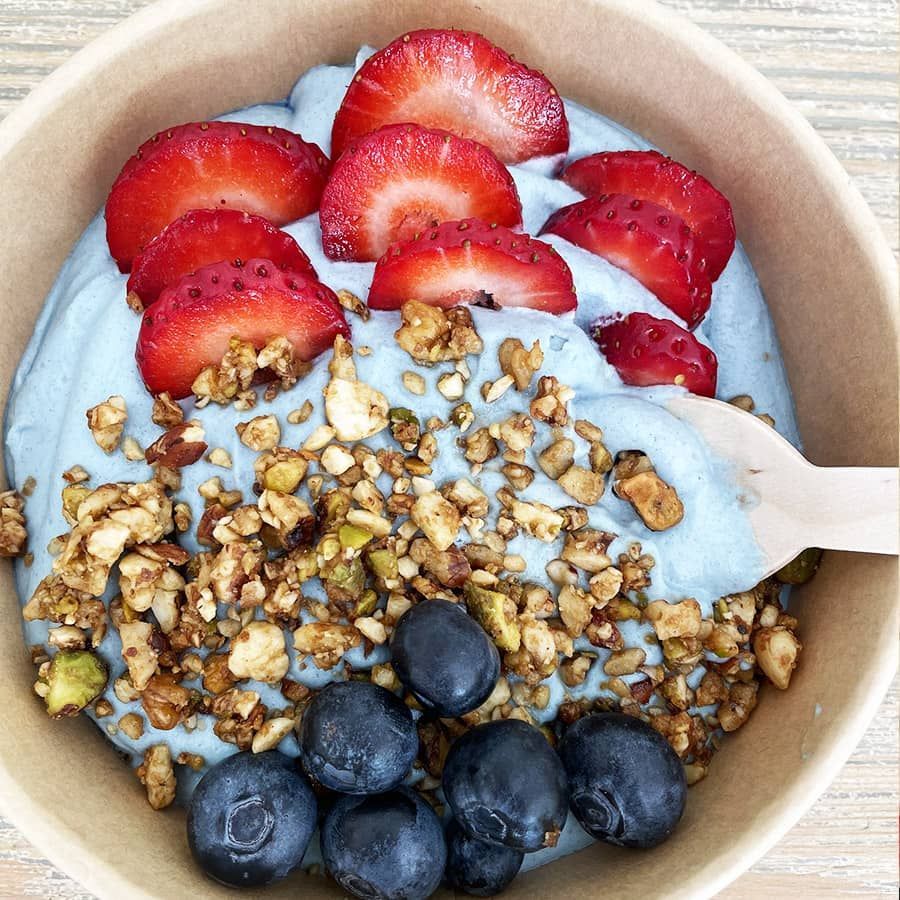 A bowl of food with strawberries blueberries and granola