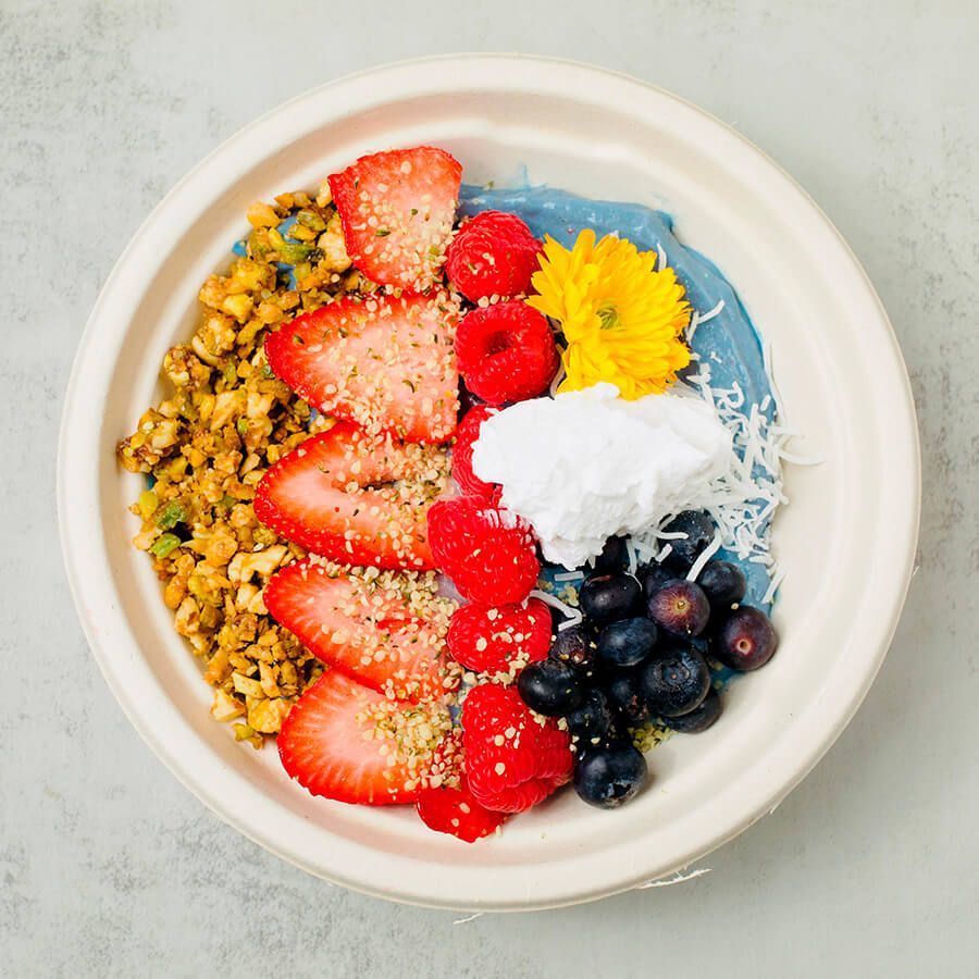 A bowl of blueberry smoothie with strawberries and walnuts