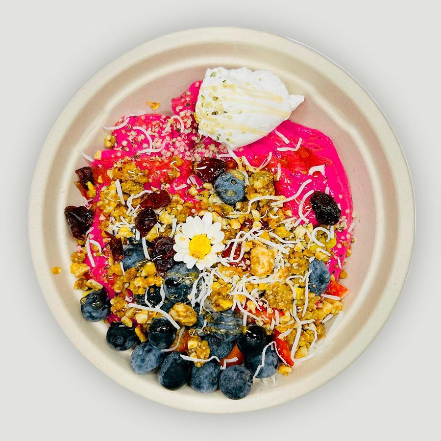 A bowl of food with strawberries and blueberries and a spoon in it