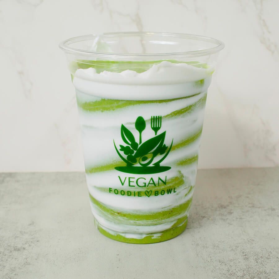 A green smoothie in a plastic cup with a red and white striped straw