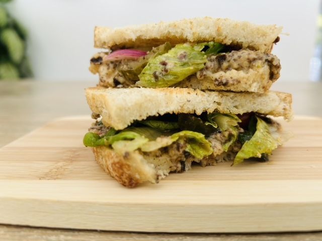 A sandwich is stacked on top of each other on a wooden cutting board.