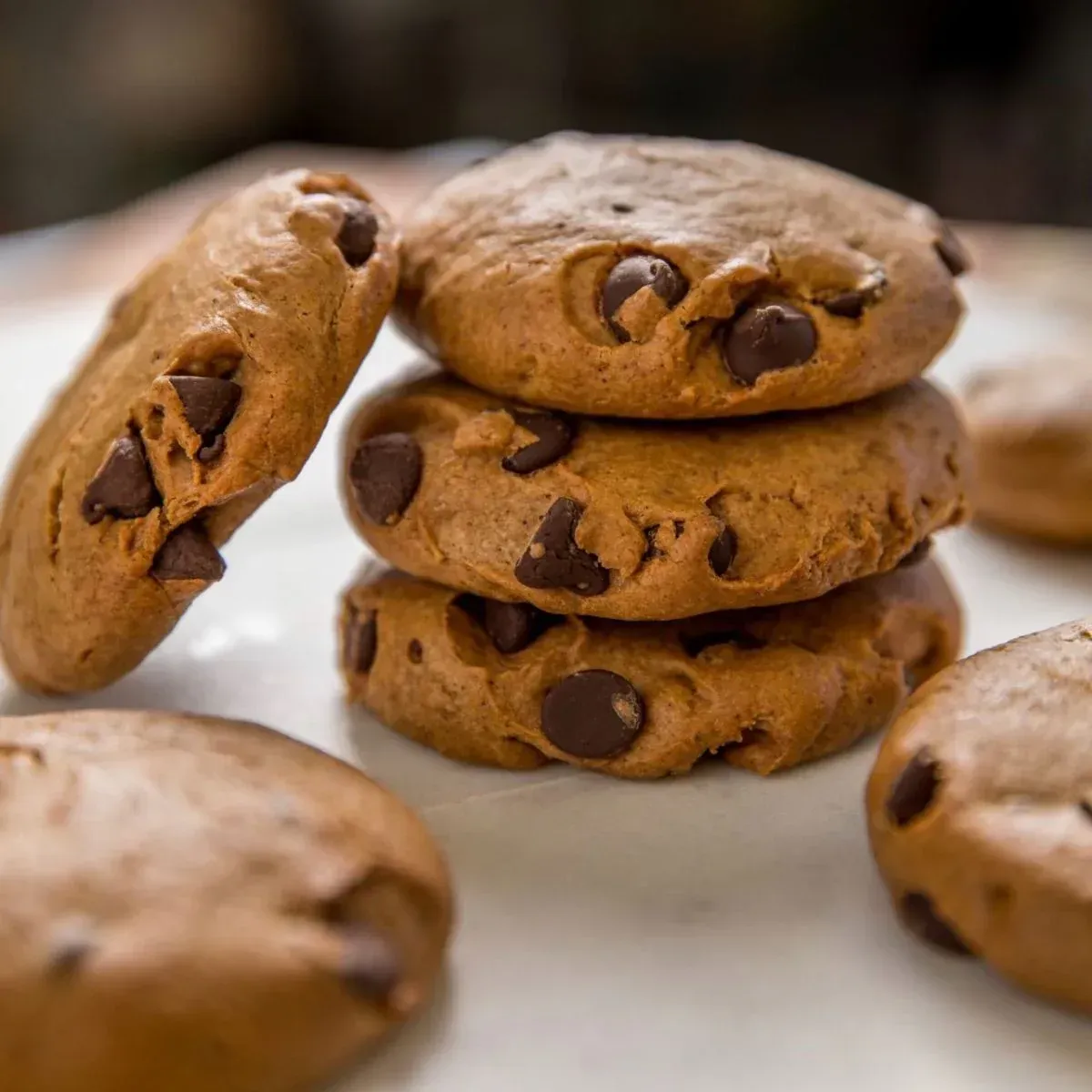 Chocolate chip cookies are stacked on top of each other on a table.