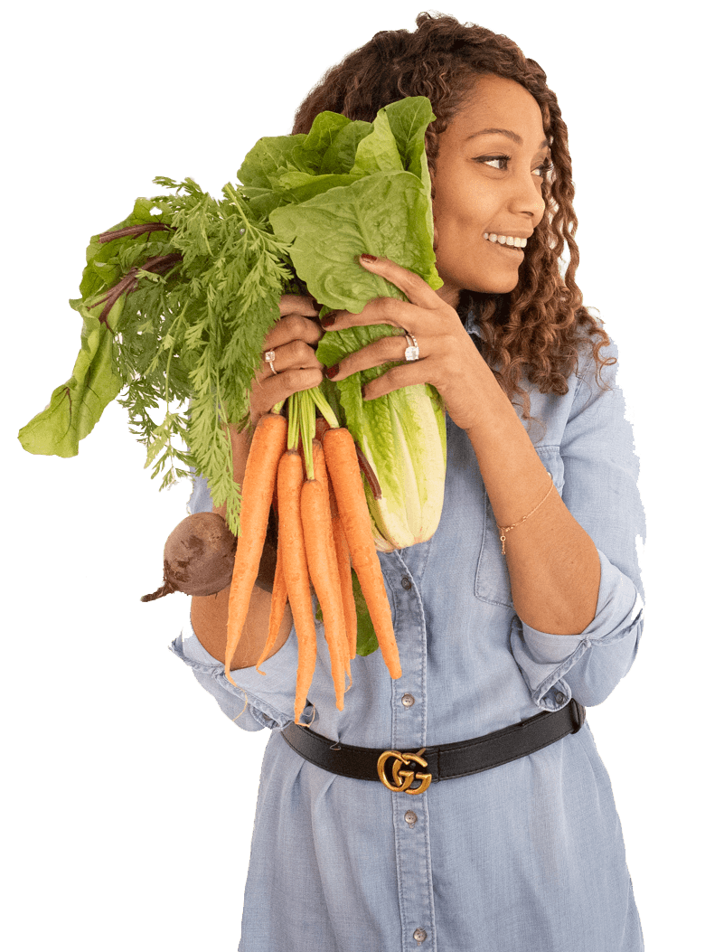 A woman is holding a bunch of carrots and lettuce.