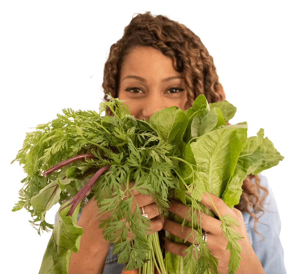 A woman is holding a bunch of green vegetables in front of her face.
