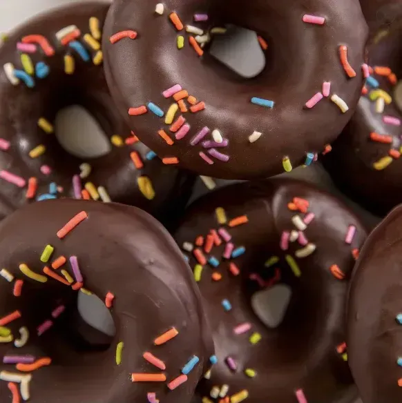 A pile of chocolate donuts with sprinkles on them