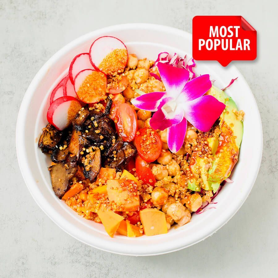A bowl of food with avocado , chickpeas , sweet potatoes , tomatoes and cabbage.