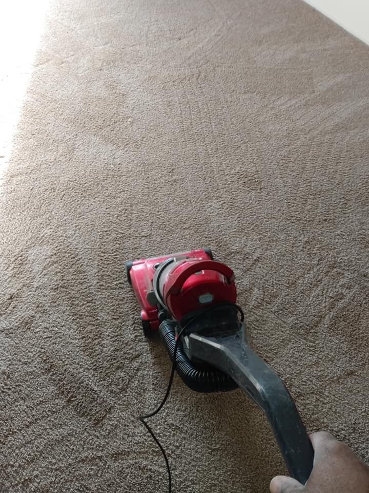 Red vacuum cleaner on beige carpet in a room.