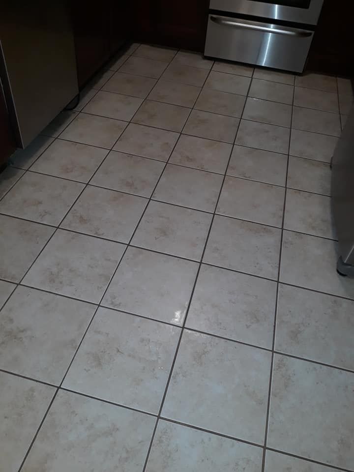 Tiled kitchen floor with stainless steel appliances at the far end