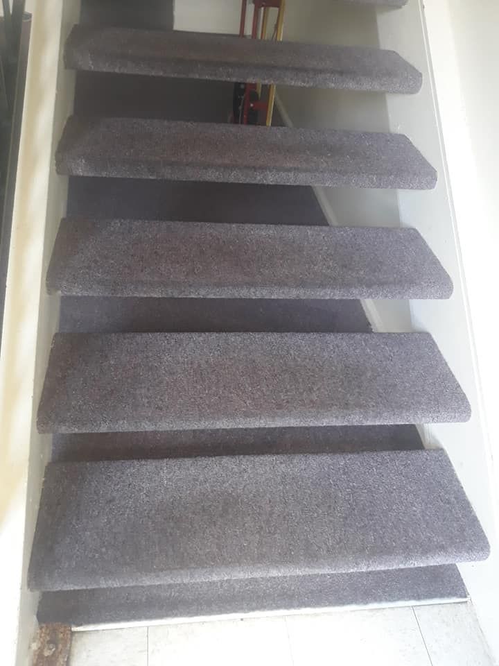 Carpeted stairs ascending indoors with gray runner and white side walls