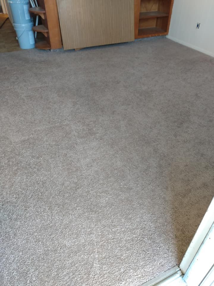 Empty carpeted room with built-in shelves and a doorway in the foreground