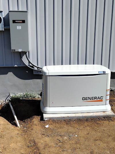 A generator is sitting in the dirt next to a building.