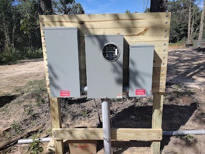 A electrical box is sitting on top of a wooden fence.