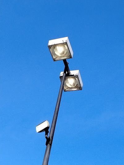 Two street lights on a pole against a blue sky