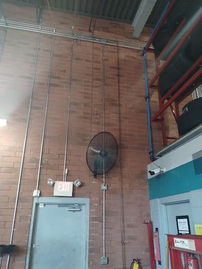 A brick wall with a fan hanging from it and a door.
