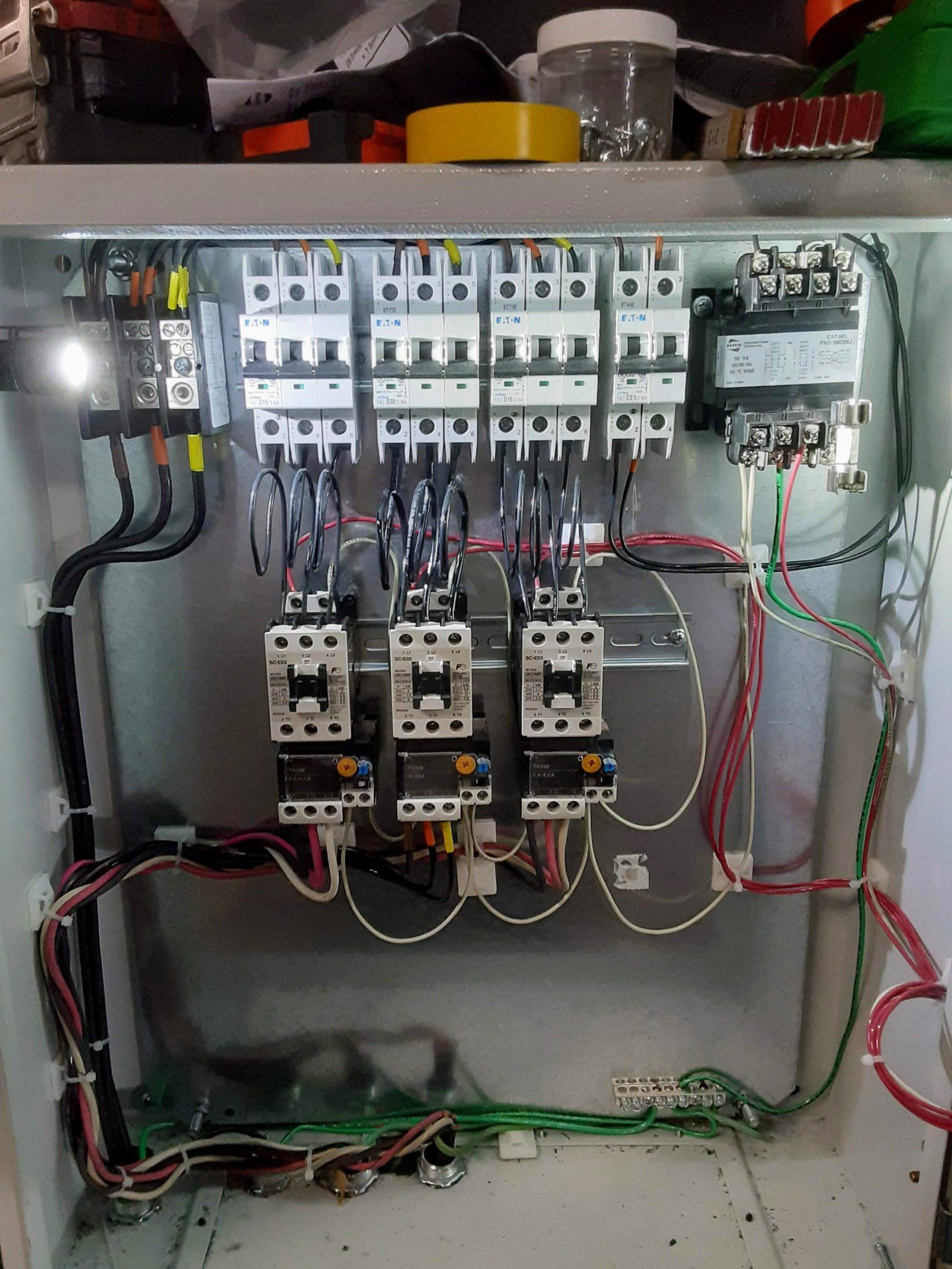The inside of a electrical box with a lot of wires coming out of it.