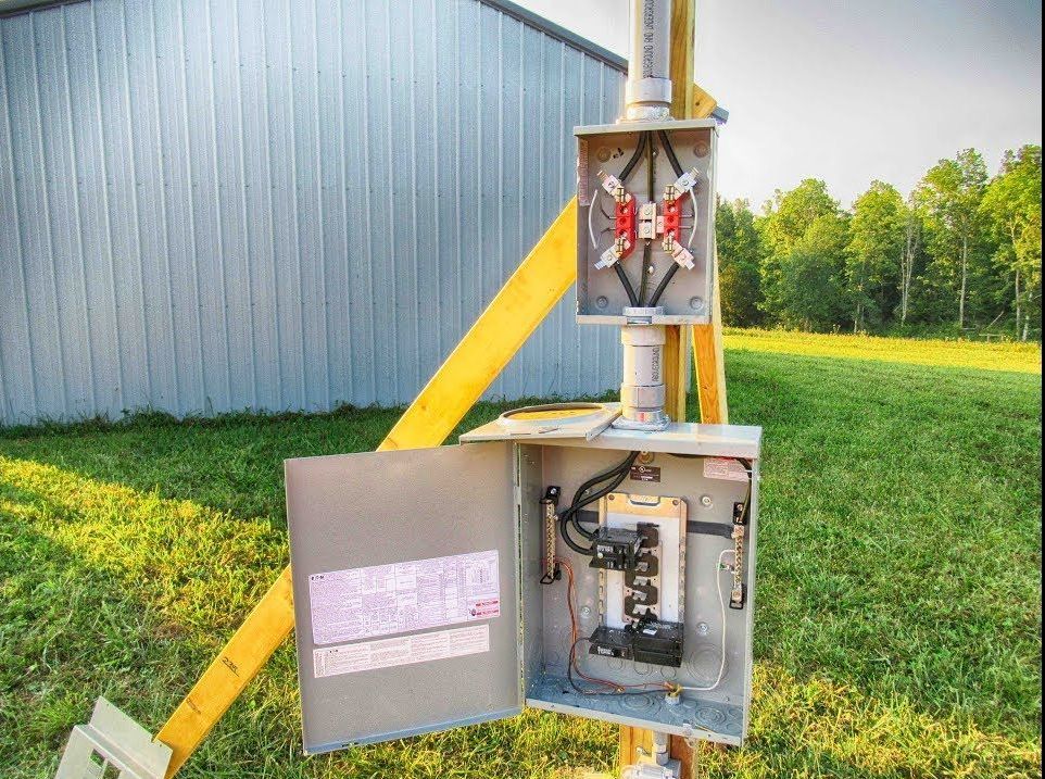An electrical box is sitting on a pole in the grass
