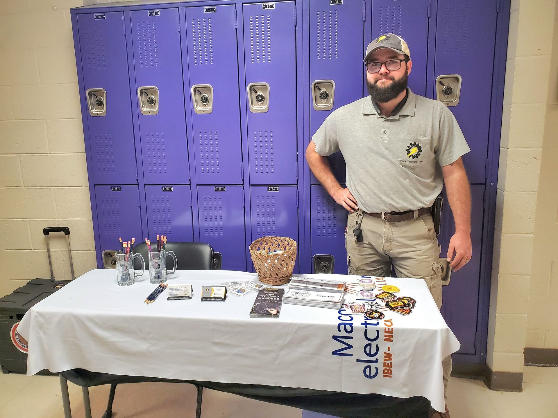 A man with a beard is standing in front of a table with a table cloth that says `` max electric ''.