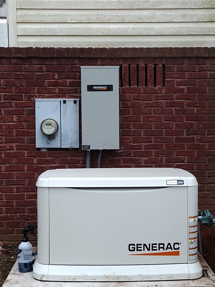 A generator is sitting in front of a brick wall.