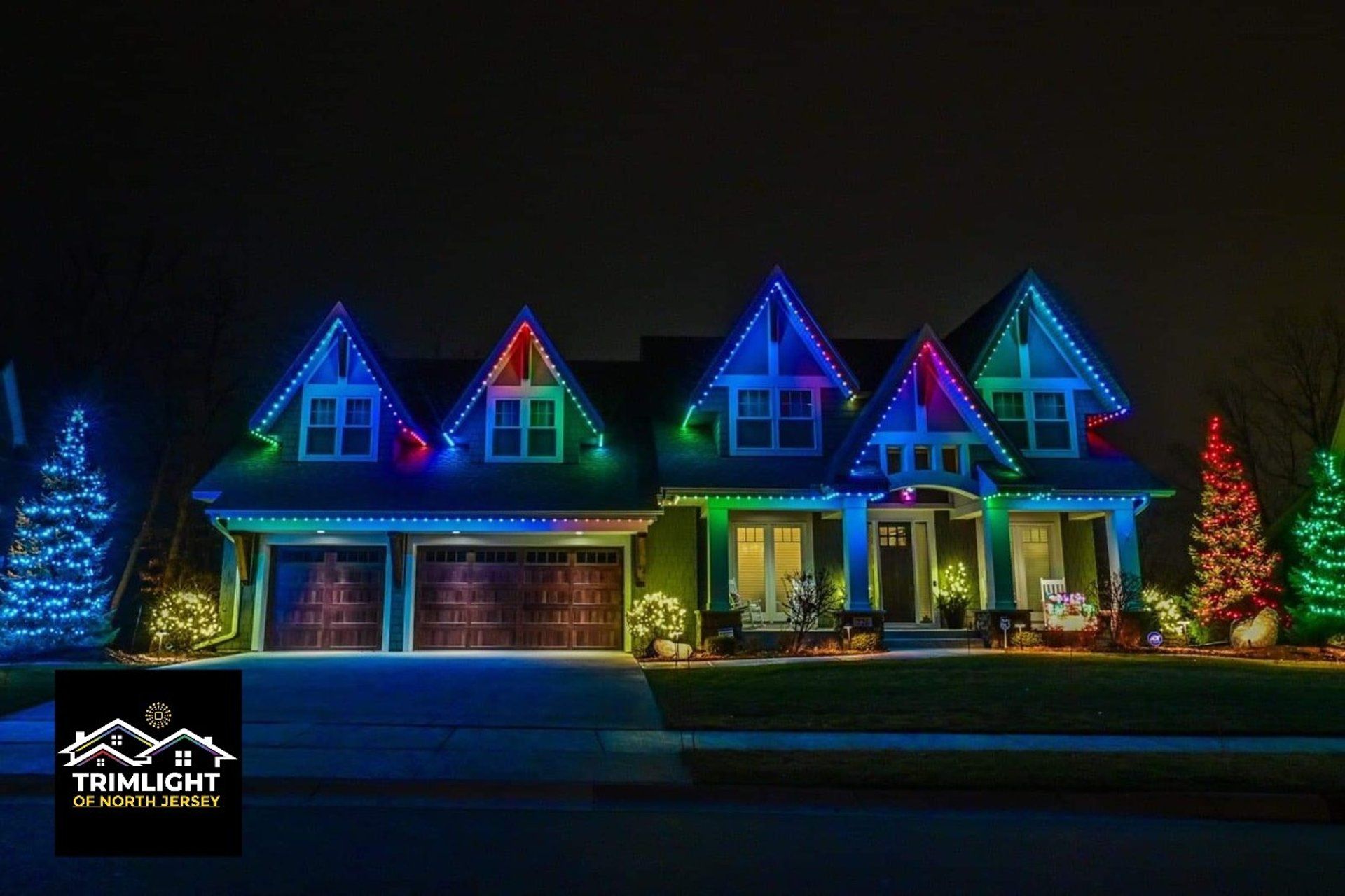 House illuminated with colorful LED lights, blue, green, and red against the dark night sky.