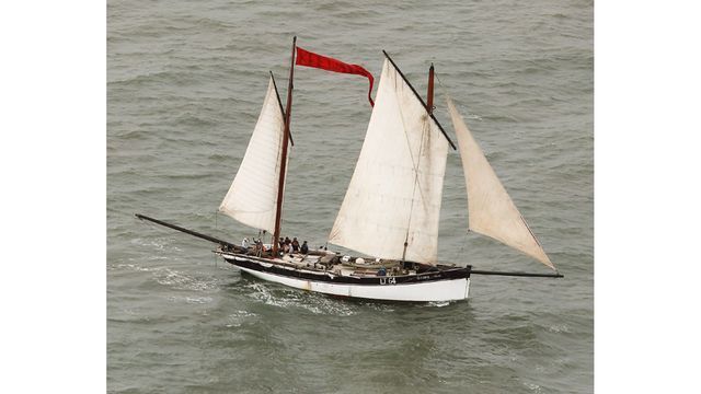 A sailboat with a red flag on the mast is floating on the water