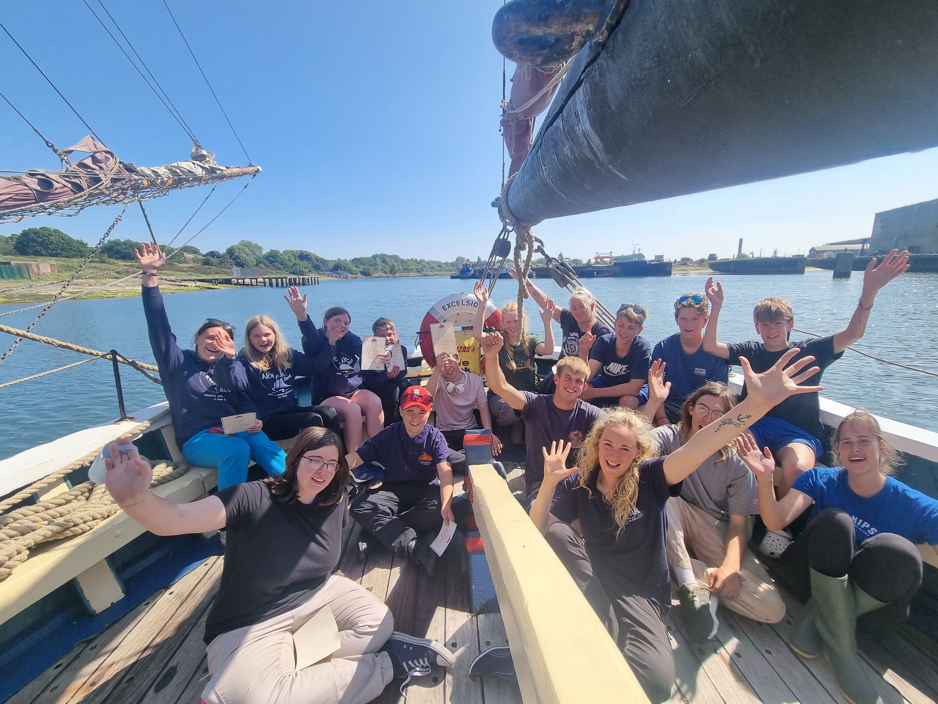 The crew from Alderman Peel High School cheer and wave from the deck of Excelsior

