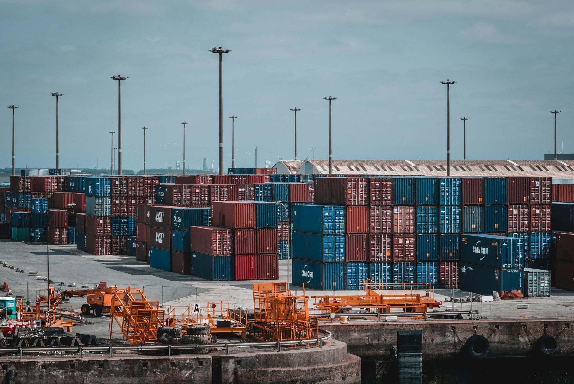 A lot of shipping containers are stacked on top of each other in a harbor.