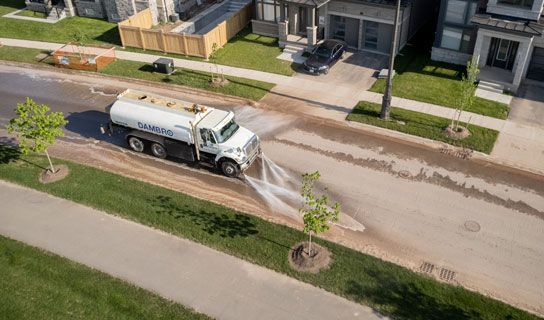 White Road Washing Truck spraying water out onto the road clearing dirt and debris