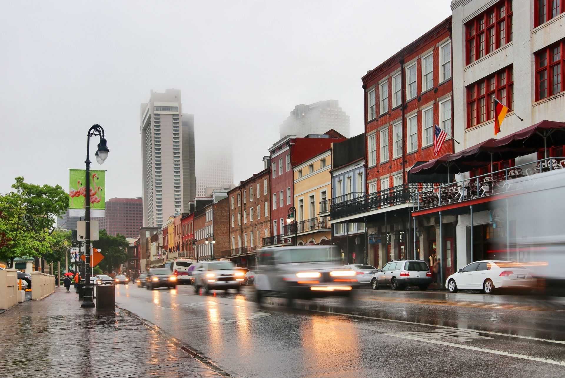 Rainy city street with cars passing historic red-brick buildings and reflections on the wet road