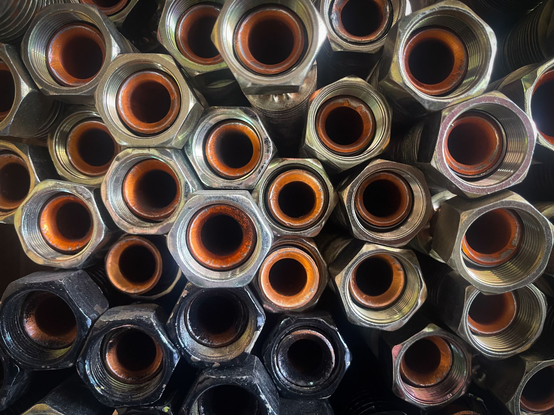 Top view of high-pressure hydraulic hose fittings with internal seals and hexagonal metal nuts. Top view of high-pressure hydraulic hose fittings with internal seals and hexagonal metal nuts.