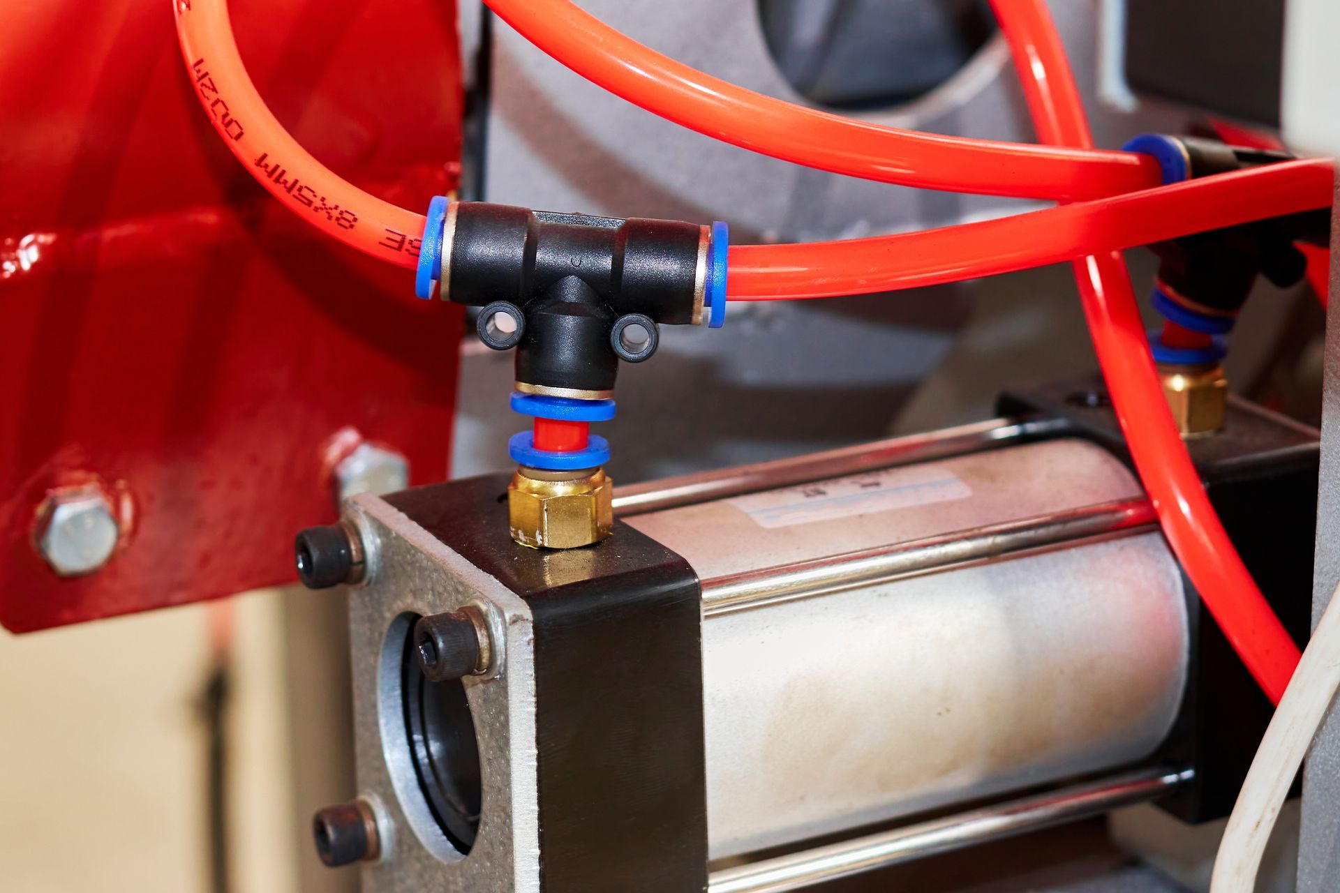 A close-up of a pneumatic system with red tubing and metal parts.