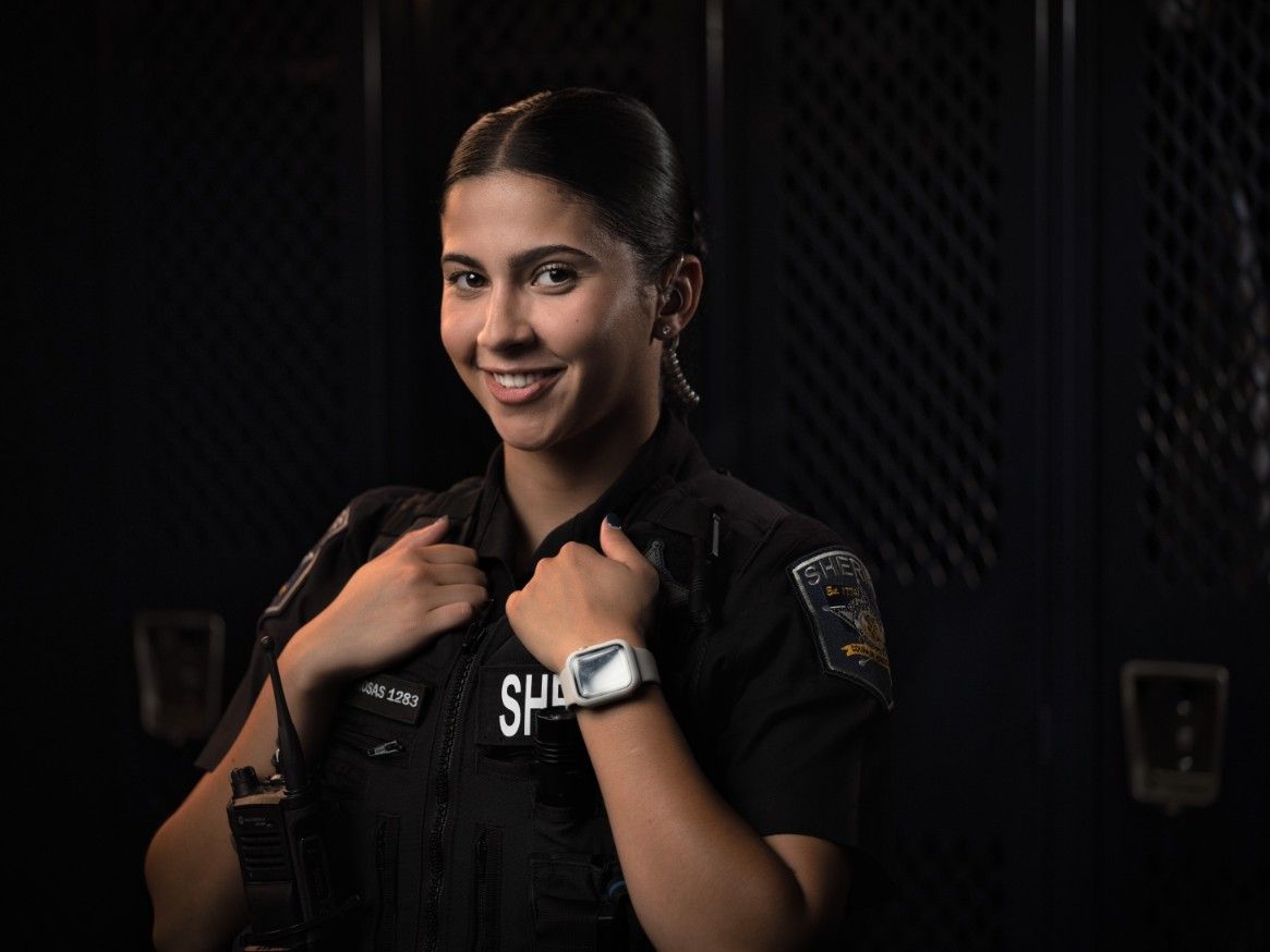 A woman in a police uniform is smiling for the camera.
