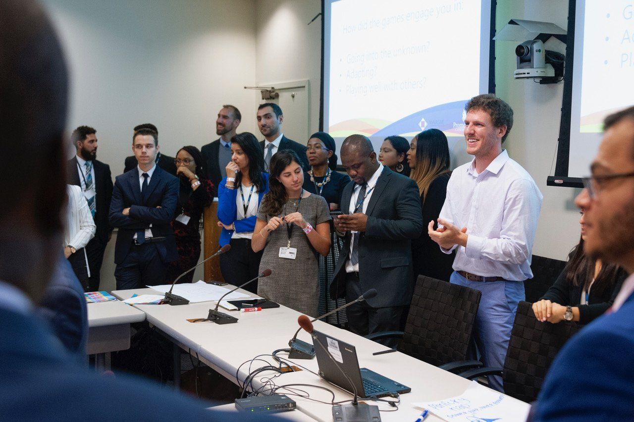 A group of people are standing around a long table in a conference room.