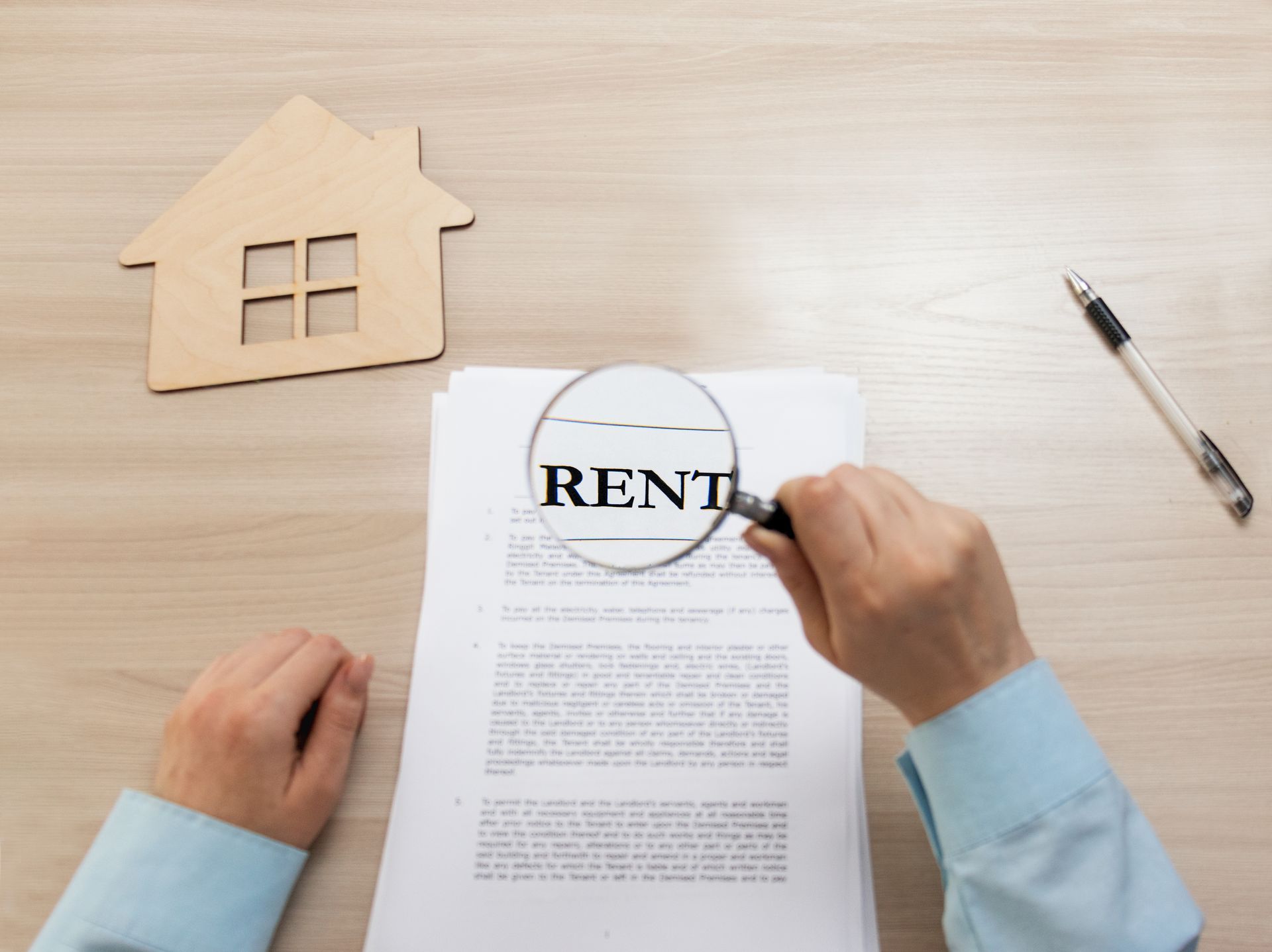 A person is holding a magnifying glass over a piece of paper that says rent.