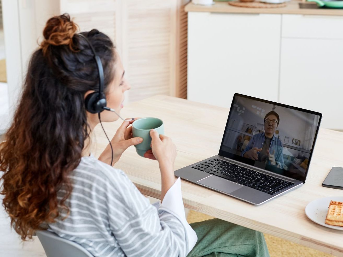 A woman is sitting at a table with a cup of coffee and a laptop computer.