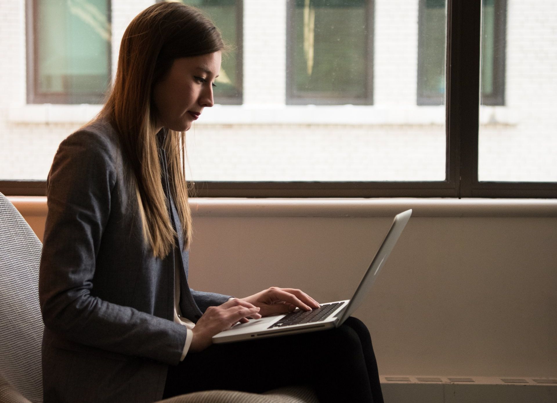 A woman is sitting on a couch using a laptop computer.