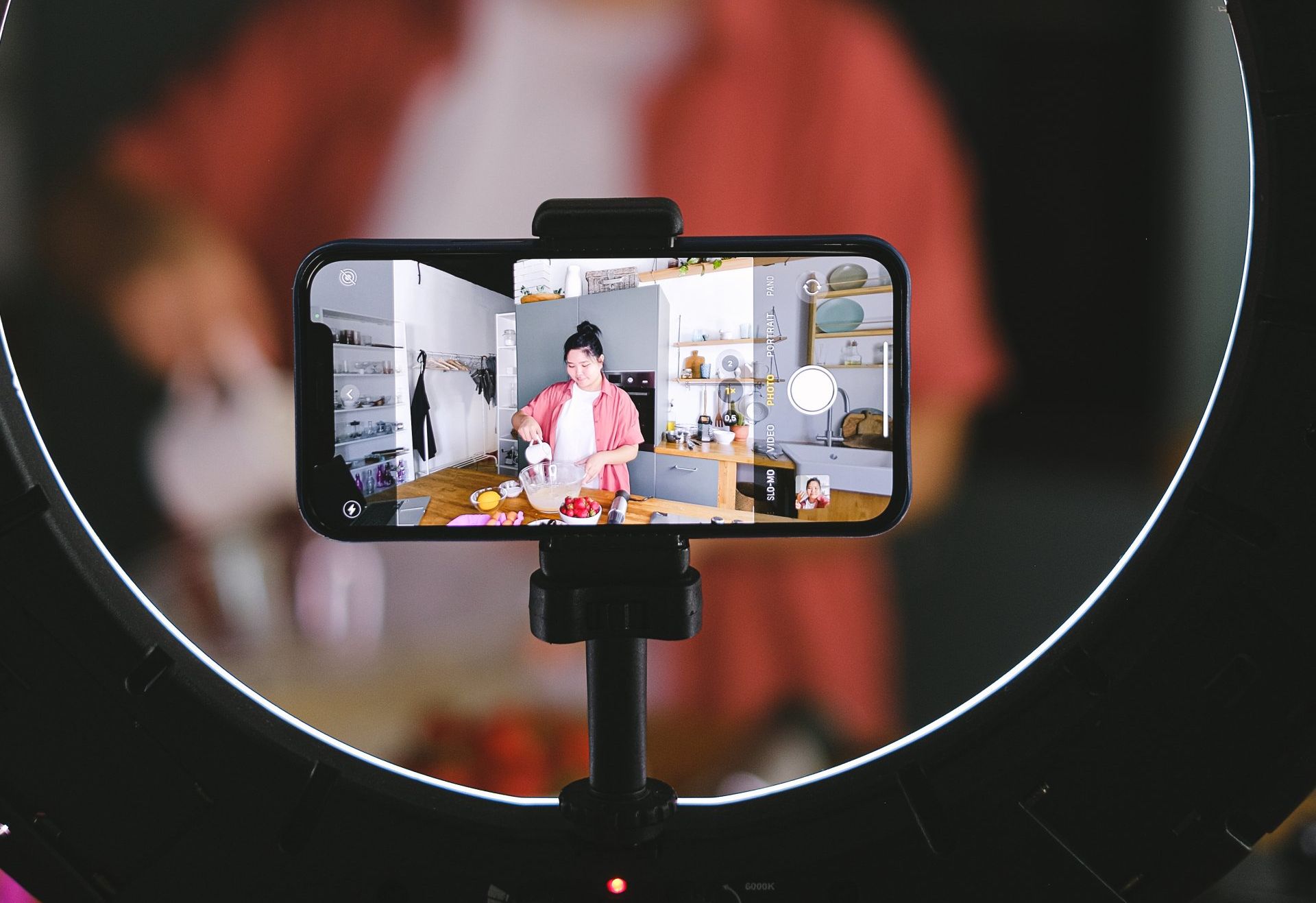 A cell phone is sitting on a tripod in front of a ring light.