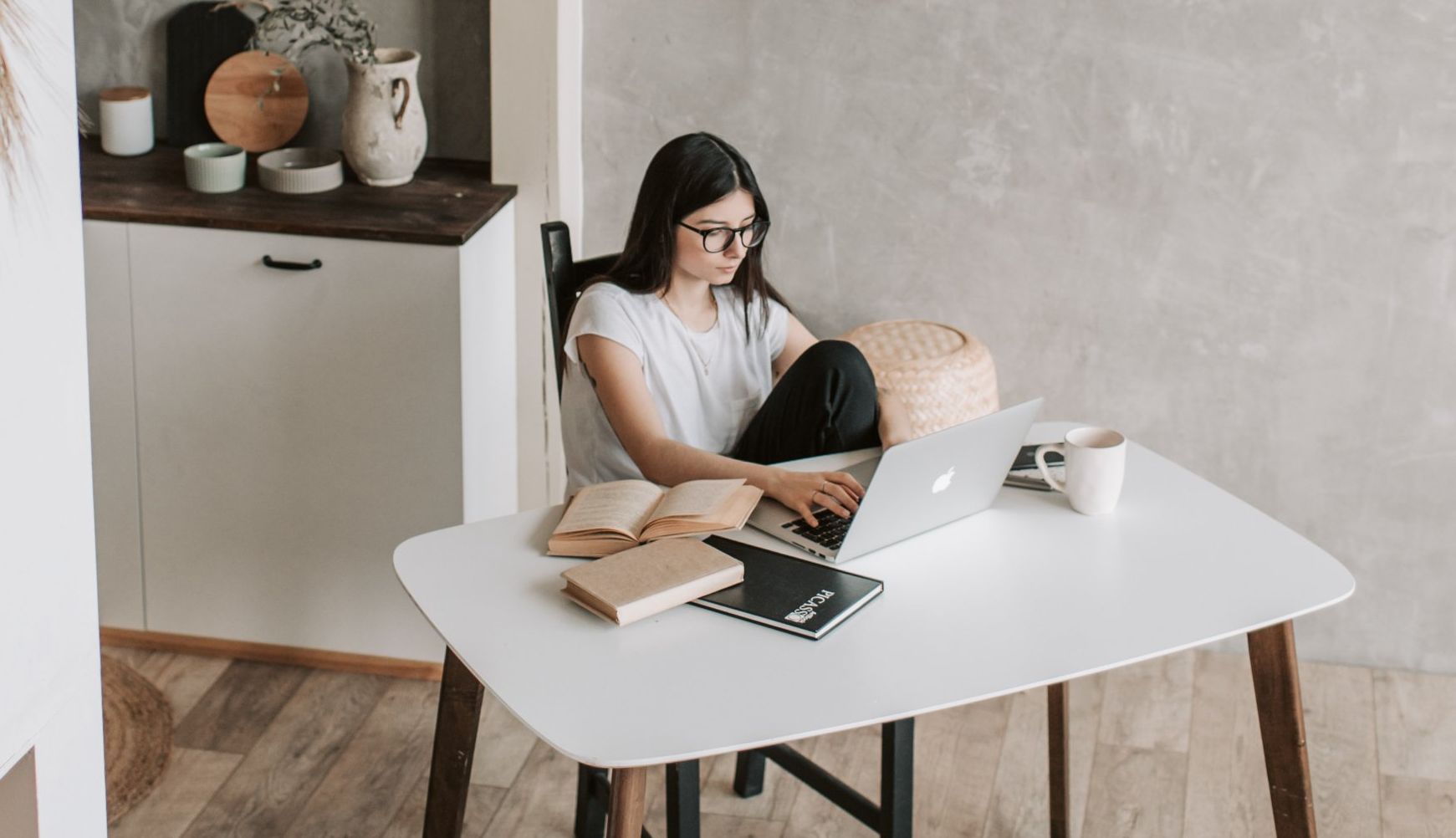 A woman is sitting at a table using a laptop computer.